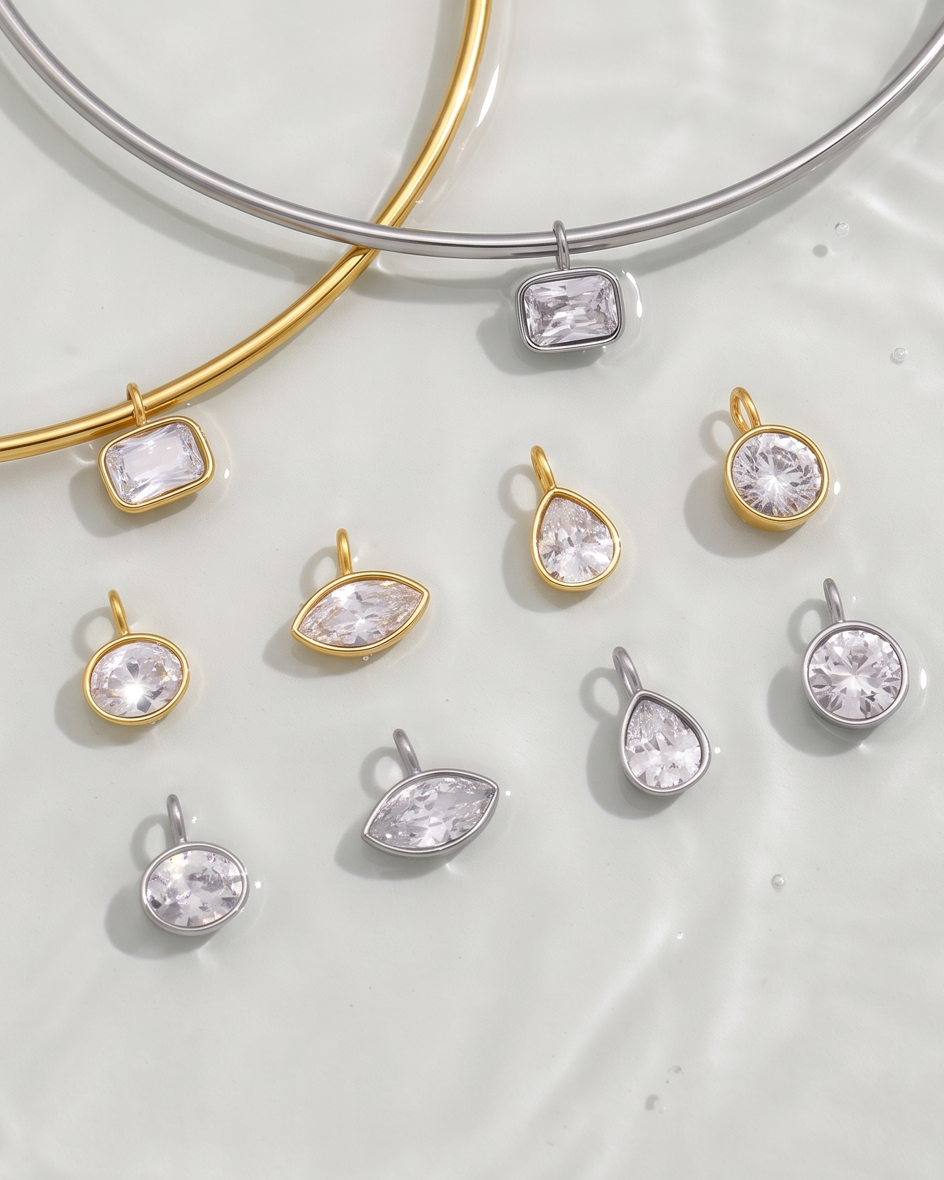 Gold and silver bangles with various crystal pendants on a light background