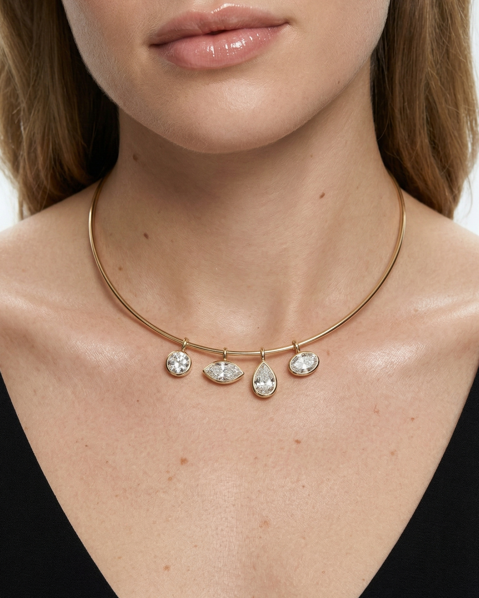 Close-up of a woman wearing a gold necklace with pendant drops on a white background