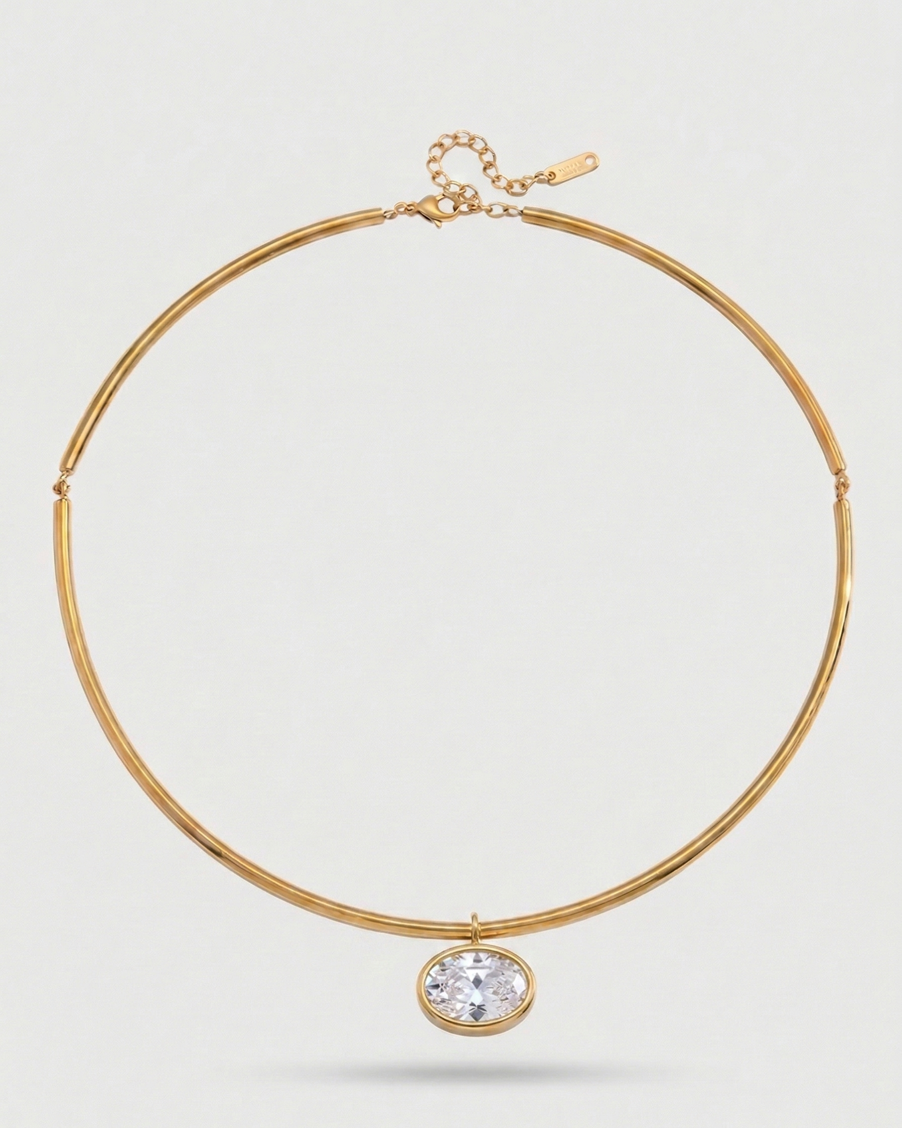 Gold necklace with a clear gemstone on a light gray background