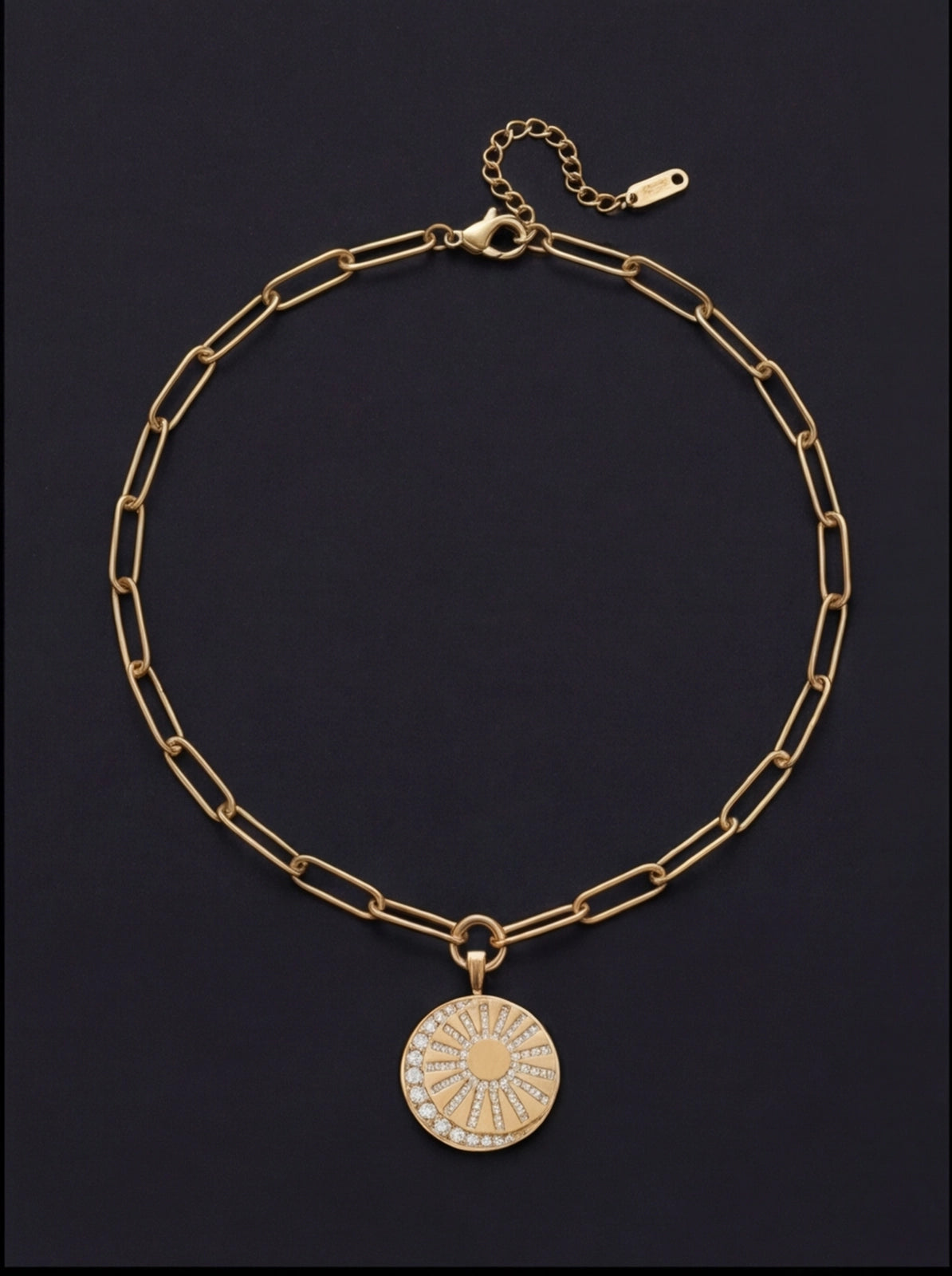 Gold chain necklace with a round pendant on a black background