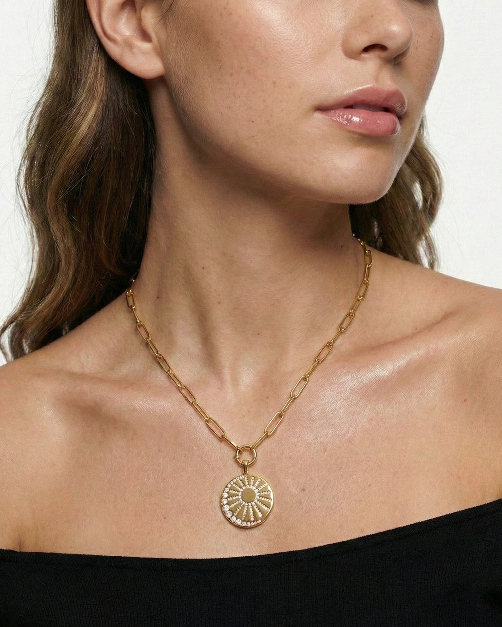 Gold necklace with a pendant worn by a model against a neutral background