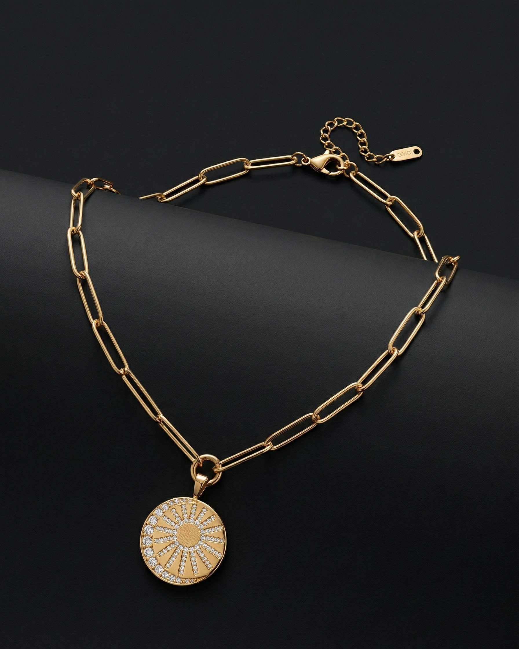 Gold chain necklace with a round pendant on a dark background
