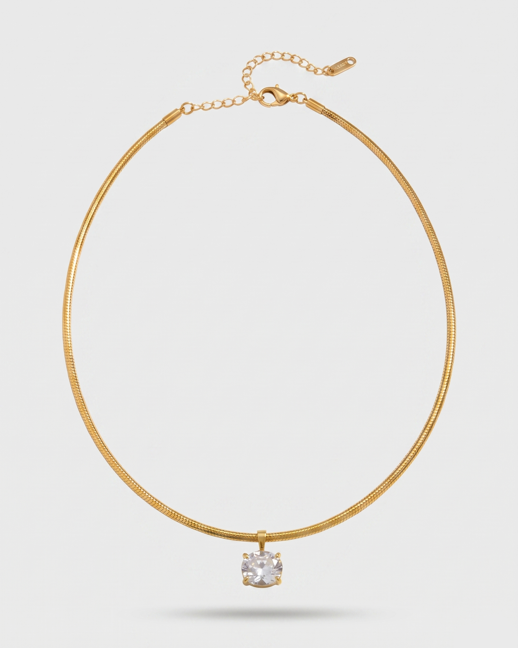 Gold necklace with a clear gemstone on a light gray background