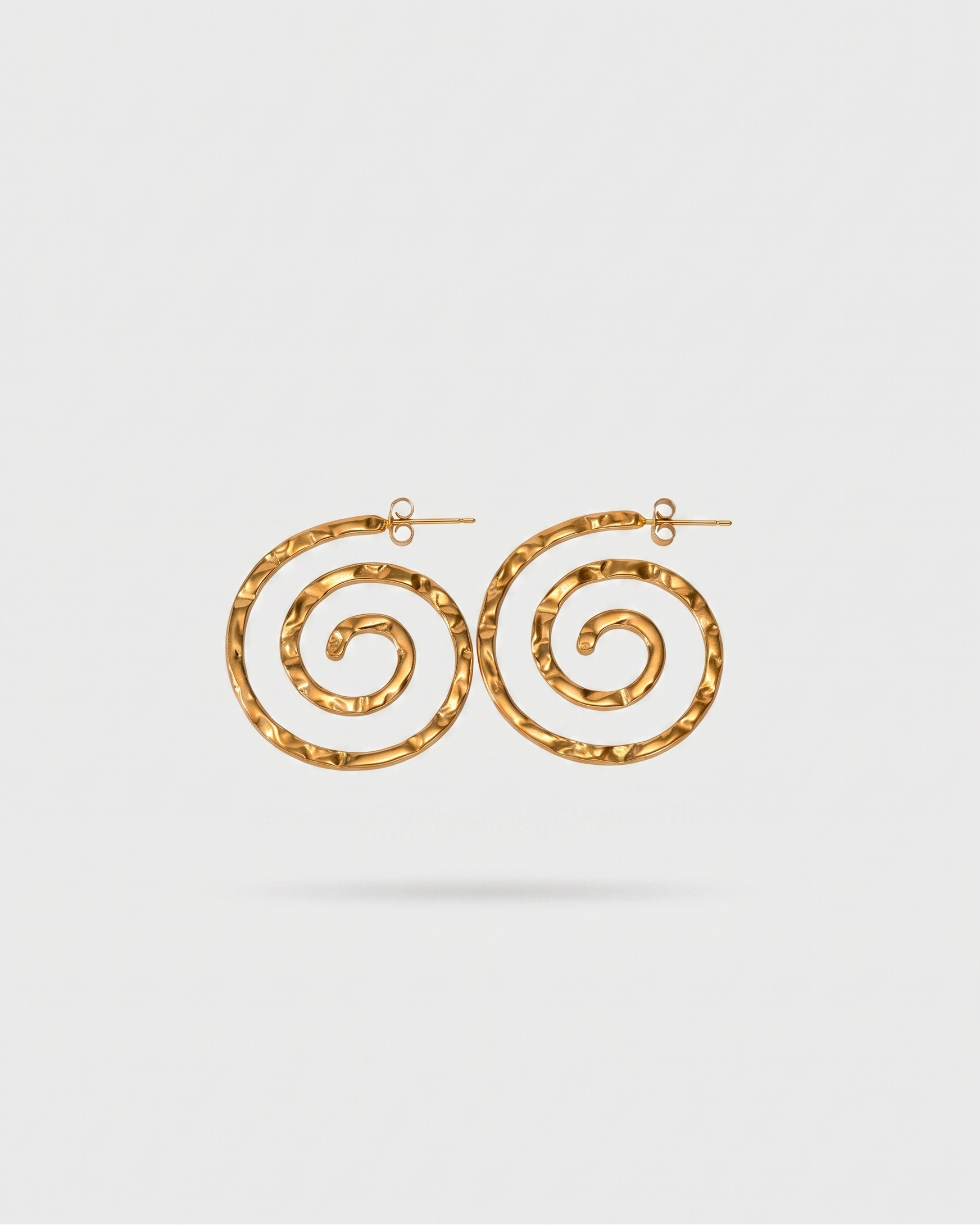 Gold spiral earrings on a light gray background