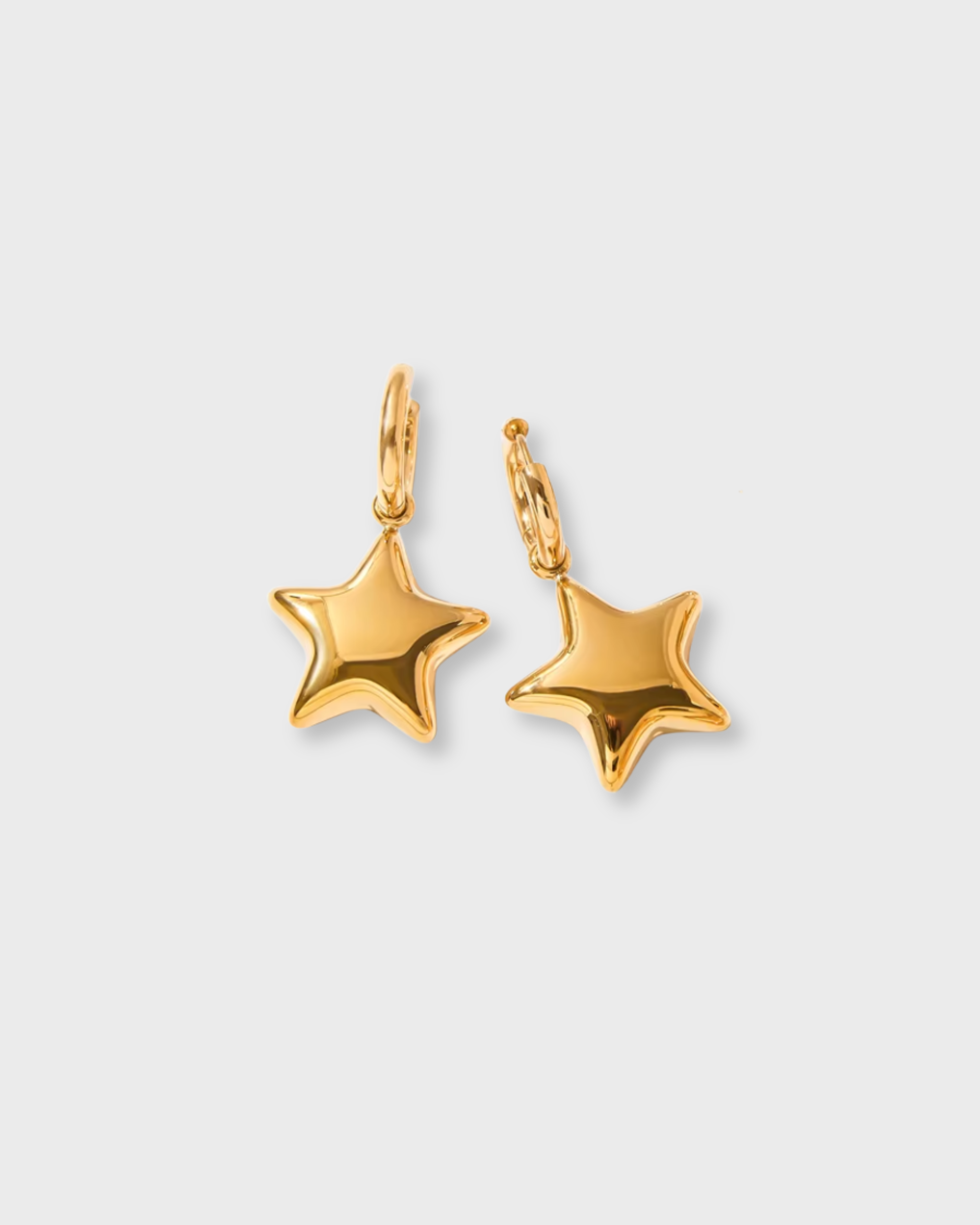 Gold star-shaped earrings on a light gray background