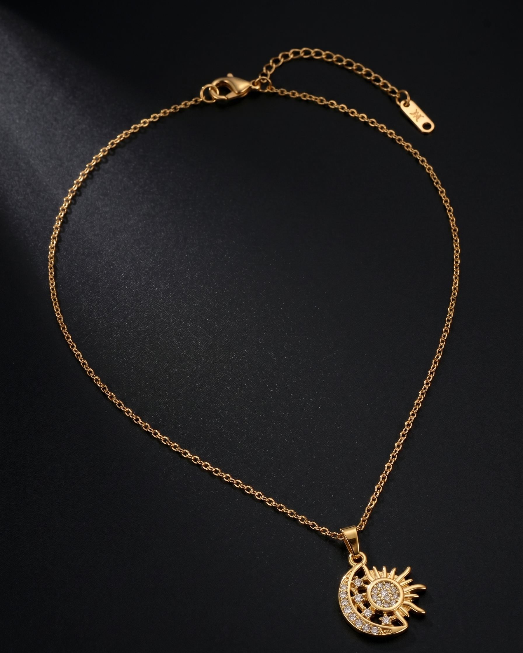 Gold bracelet with a sun and moon pendant on a black background