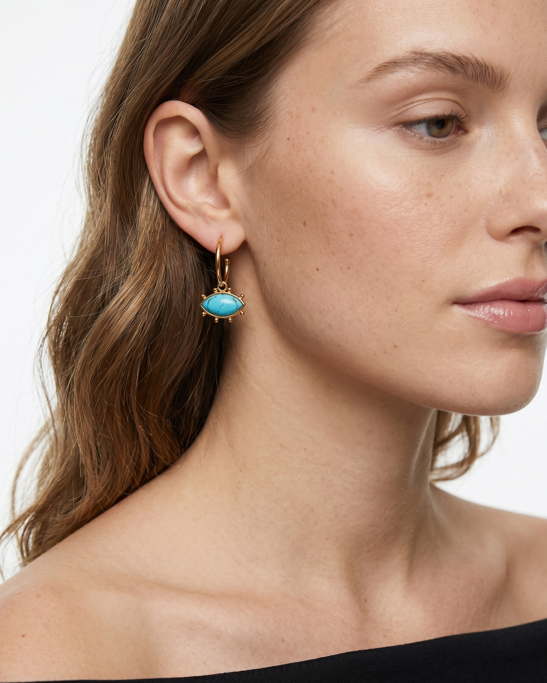 Close-up of a woman wearing a turquoise earring with gold accents.