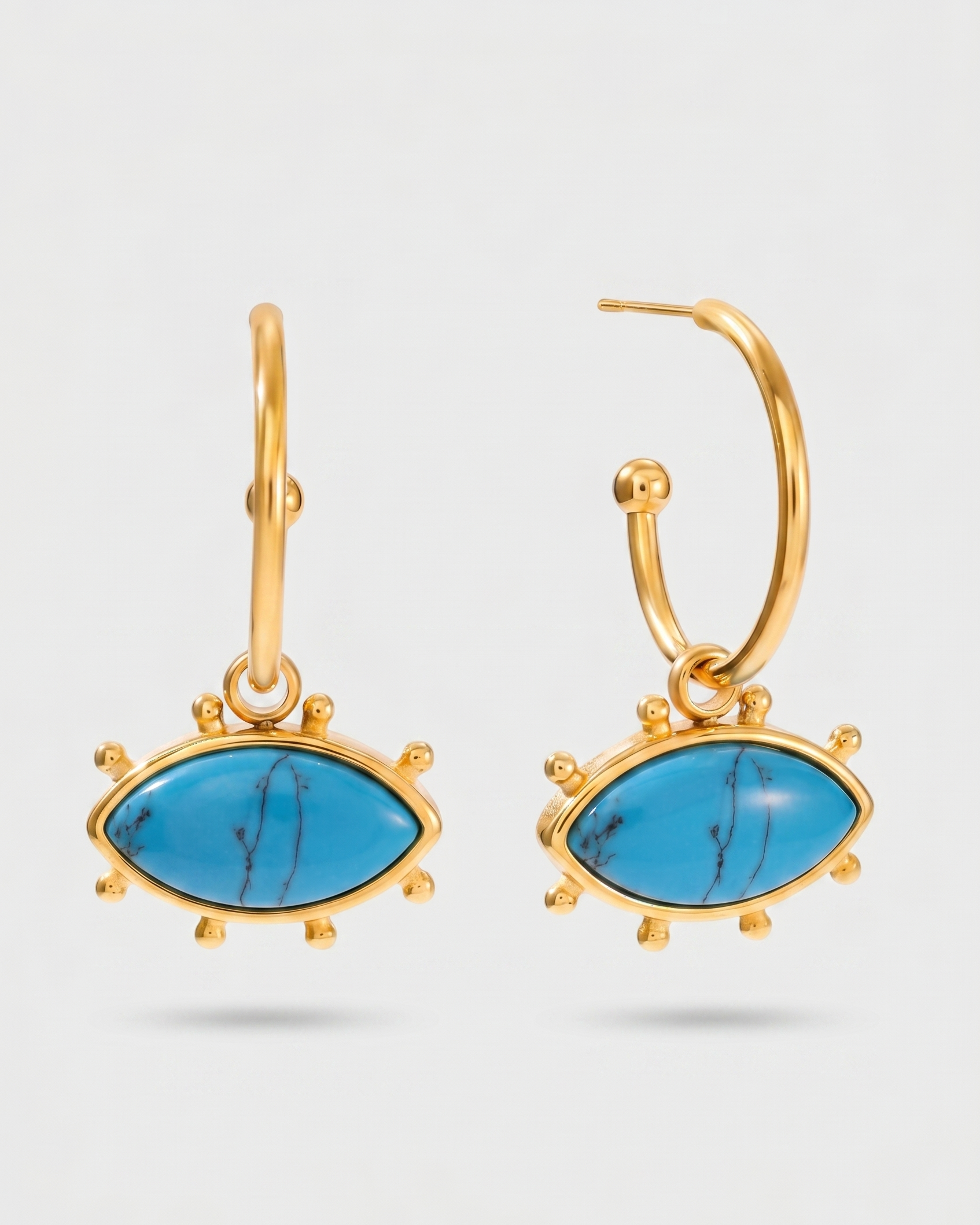 Gold earrings with blue gemstones on a light gray background