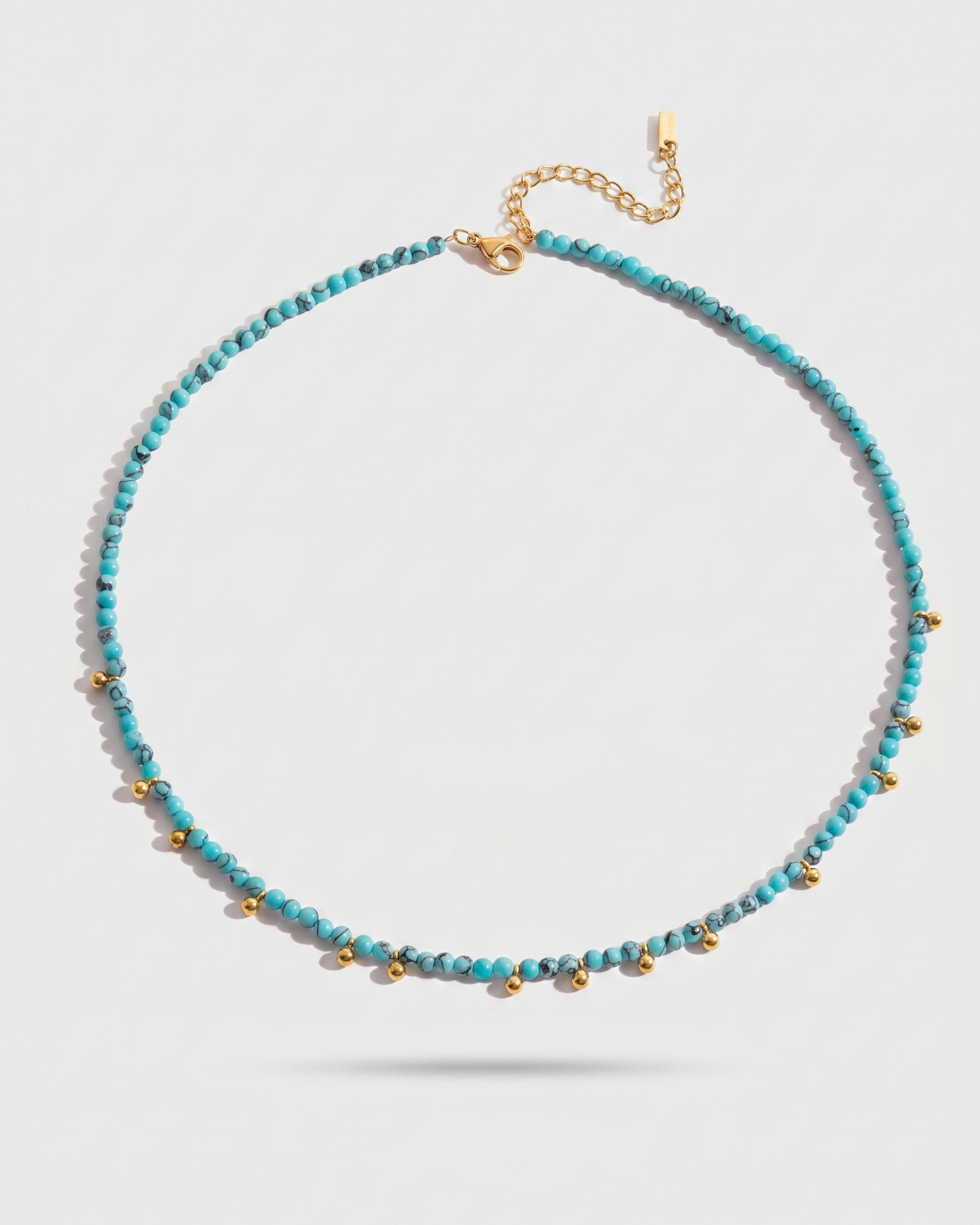 Necklace with blue beads and gold accents on a light gray background