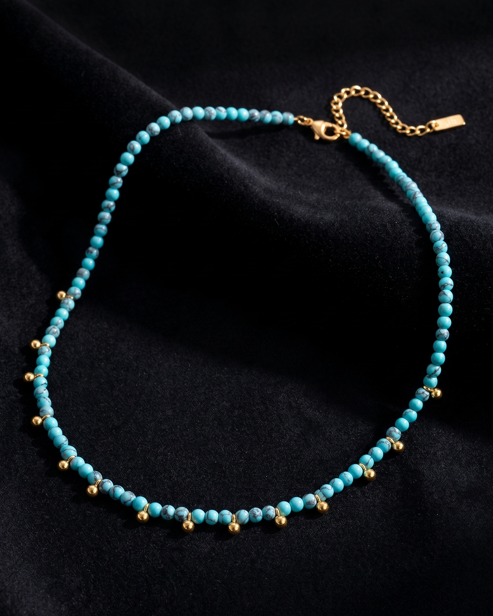 Turquoise beaded necklace with gold accents on a black background