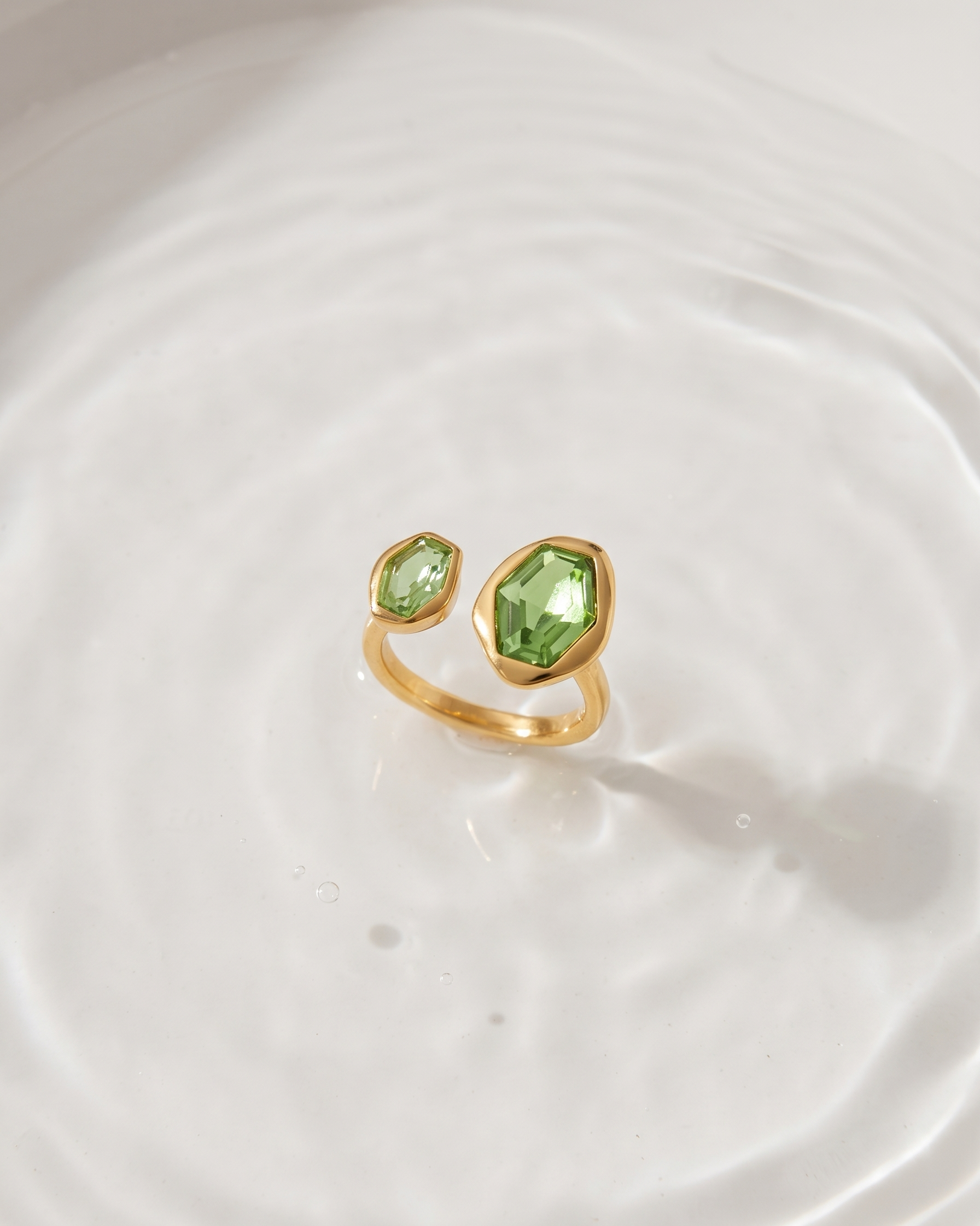 Gold ring with green gemstones on a white background