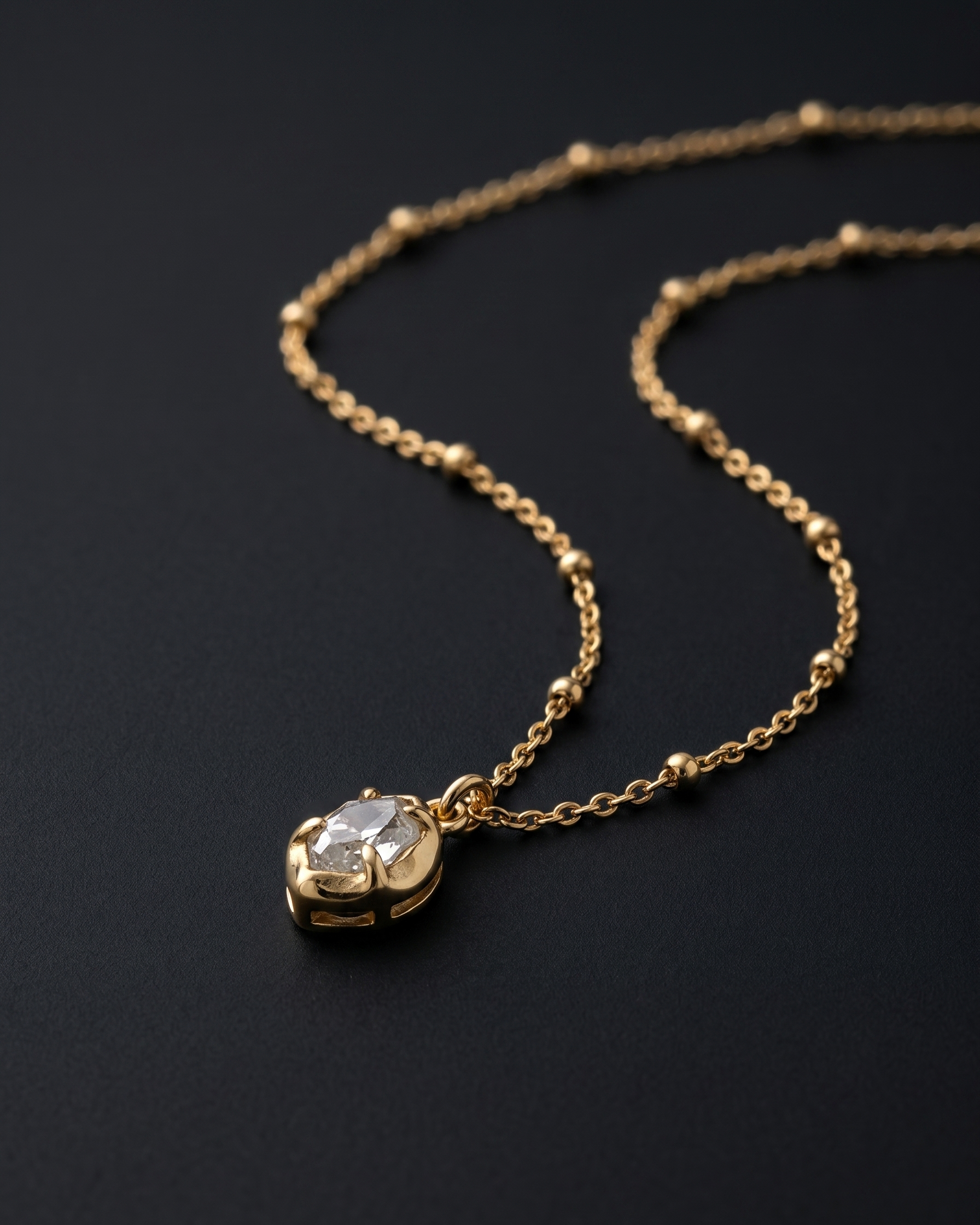 Gold necklace with a diamond pendant on a black background