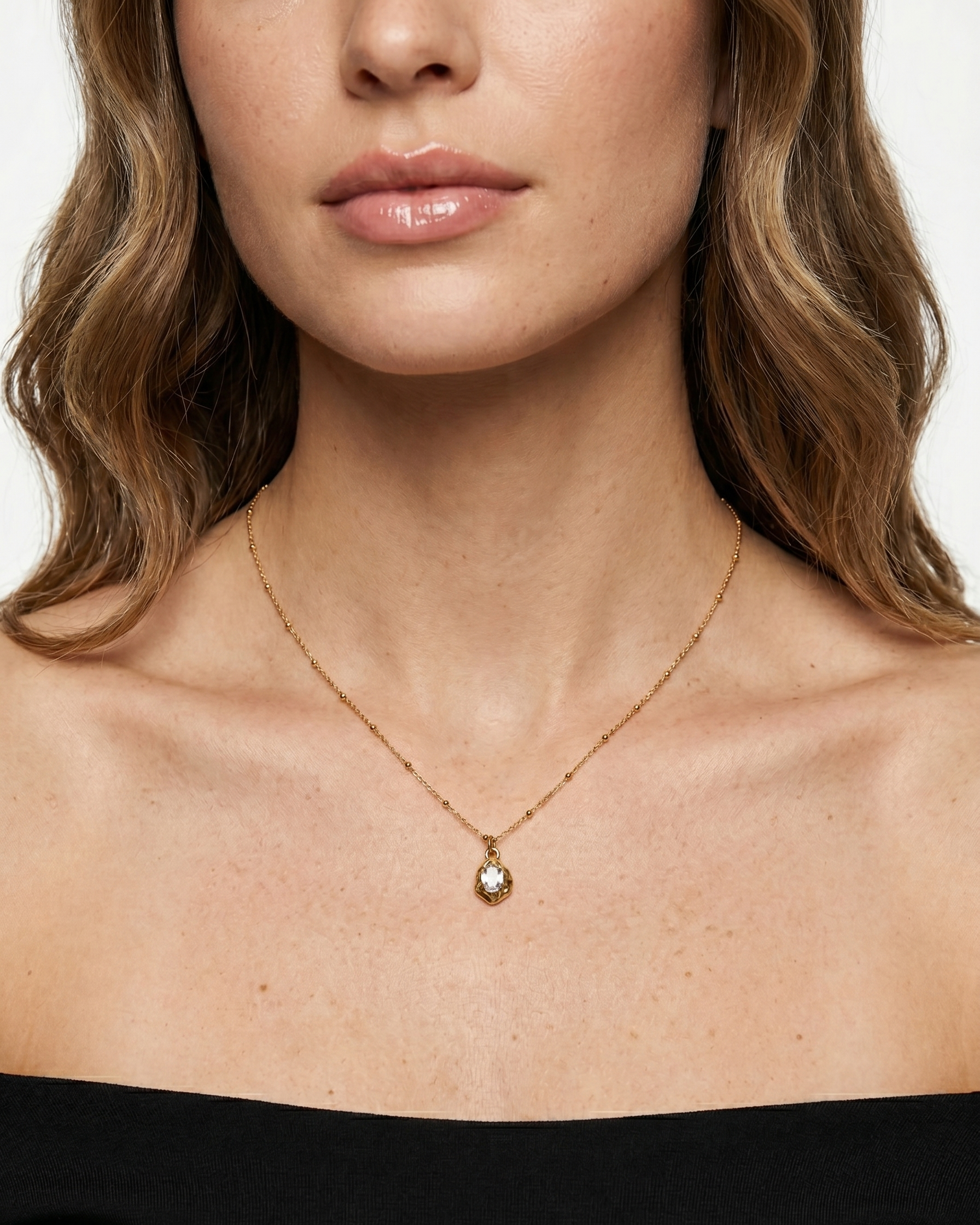 Close-up of a woman wearing a gold necklace with a pendant on a white background