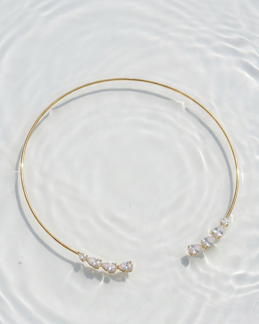 Gold choker necklace with small stones on a light background