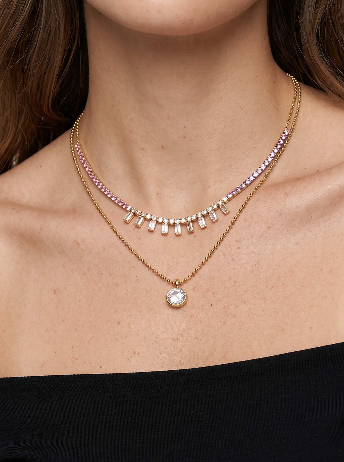 Woman wearing a delicate necklace with a clear gemstone on a plain background
