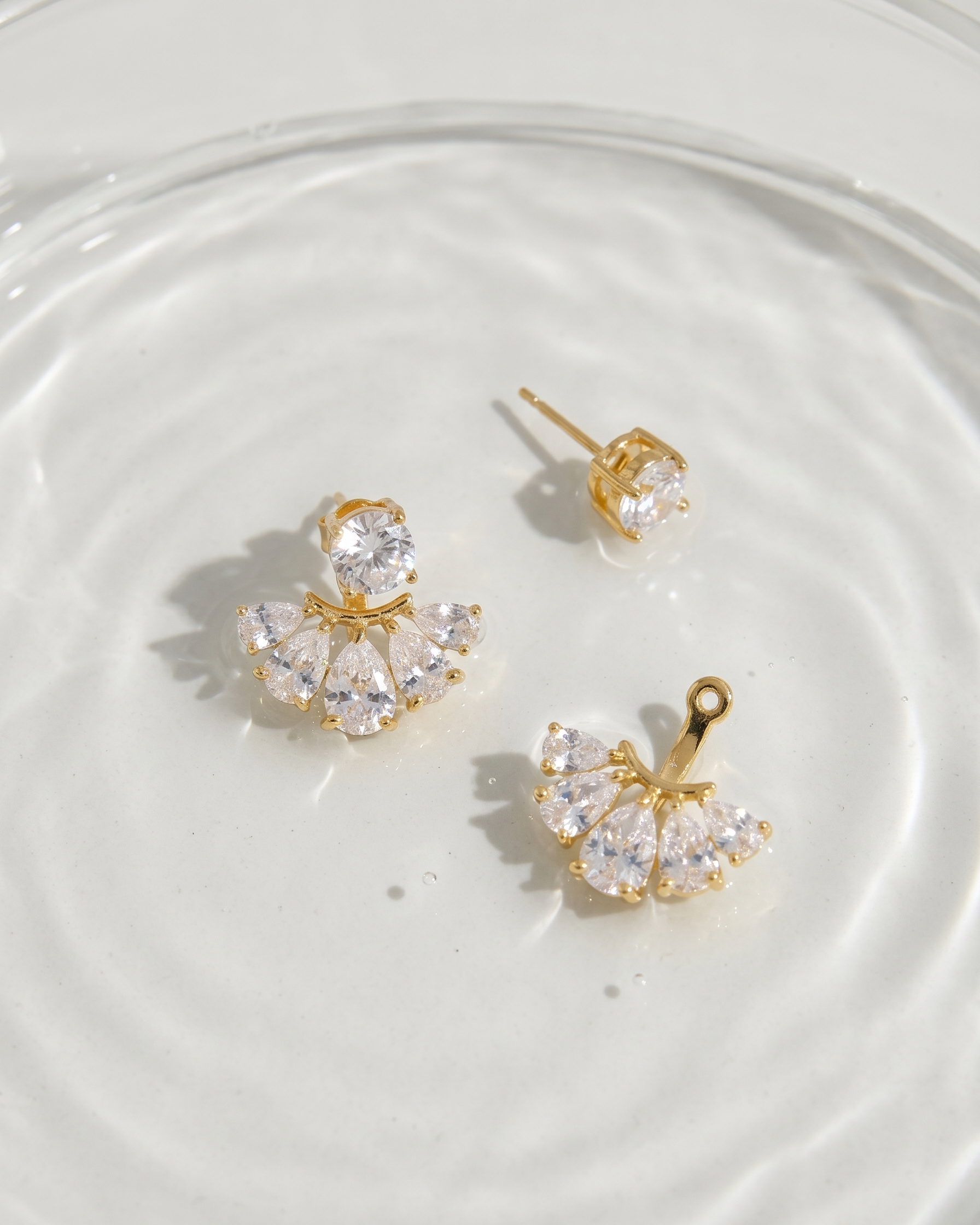 Gold butterfly earrings with clear gemstones on a white surface