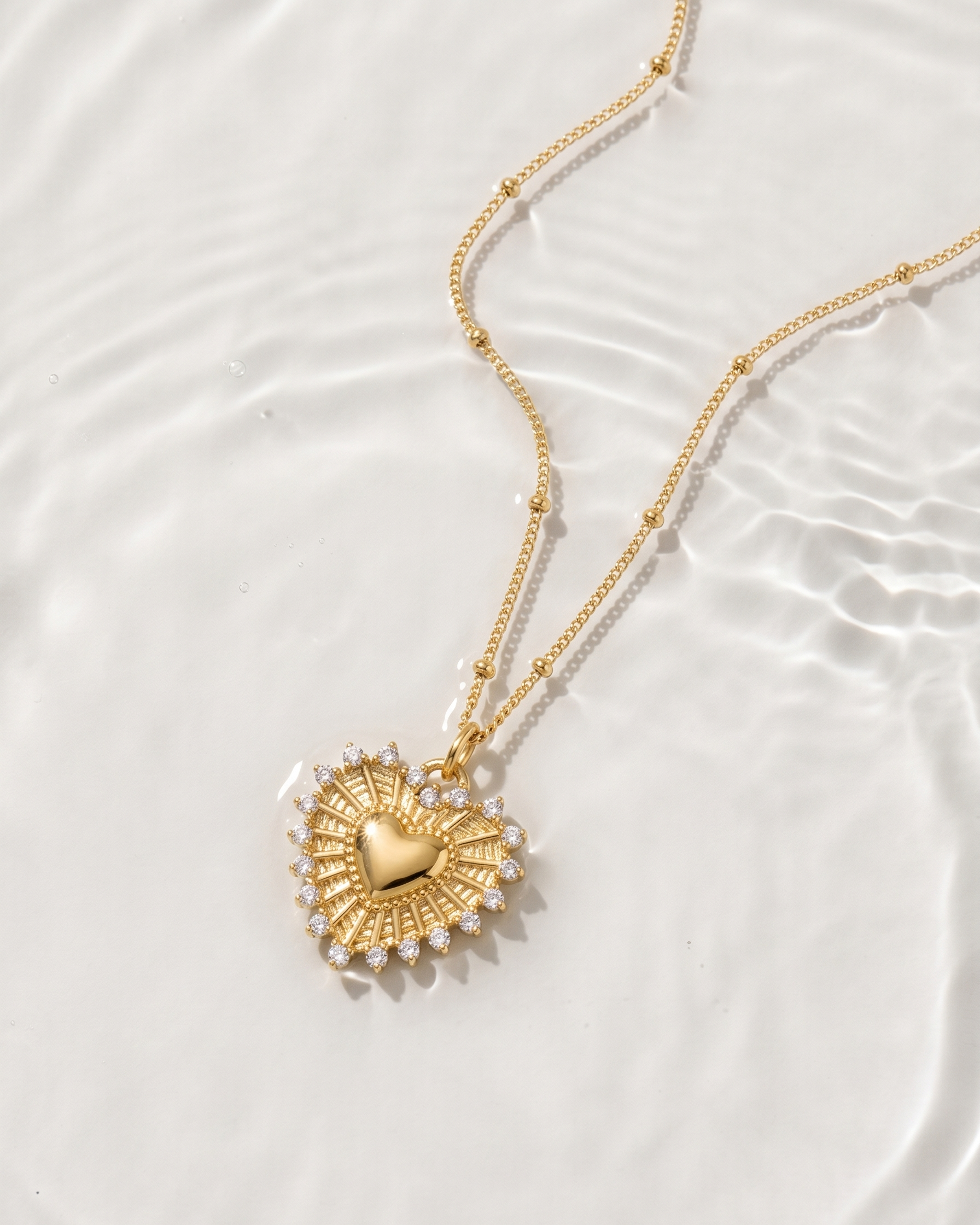 Gold necklace with a heart-shaped pendant on a white background