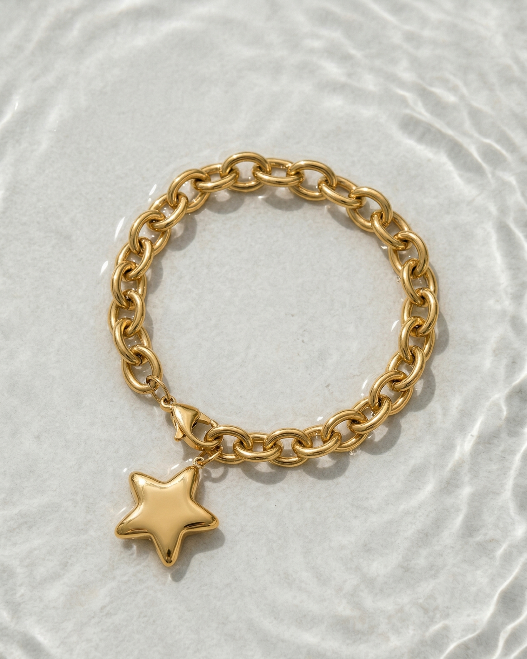 Gold chain bracelet with a star charm on a light gray background