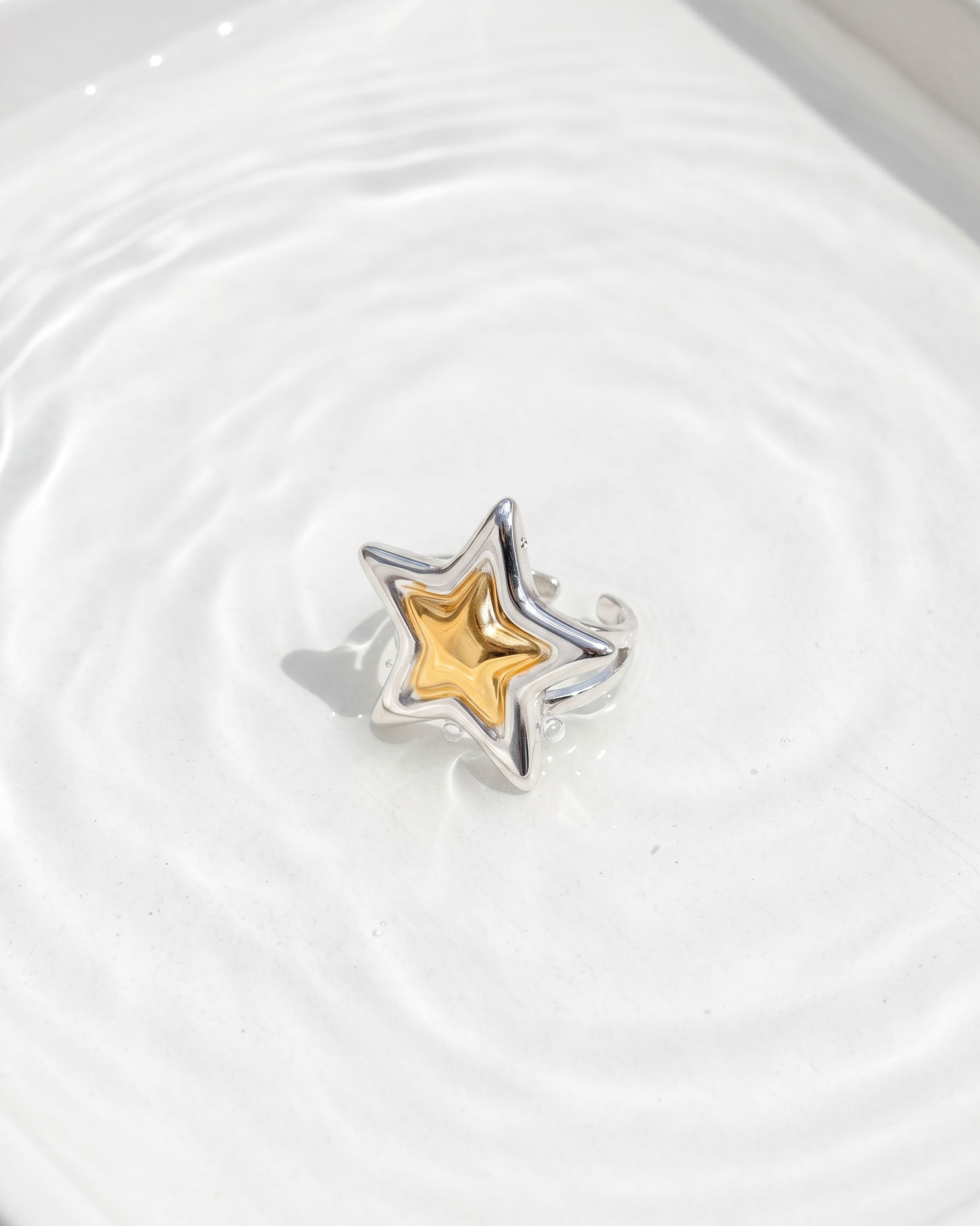 Star-shaped object with gold center and silver outline on a white surface