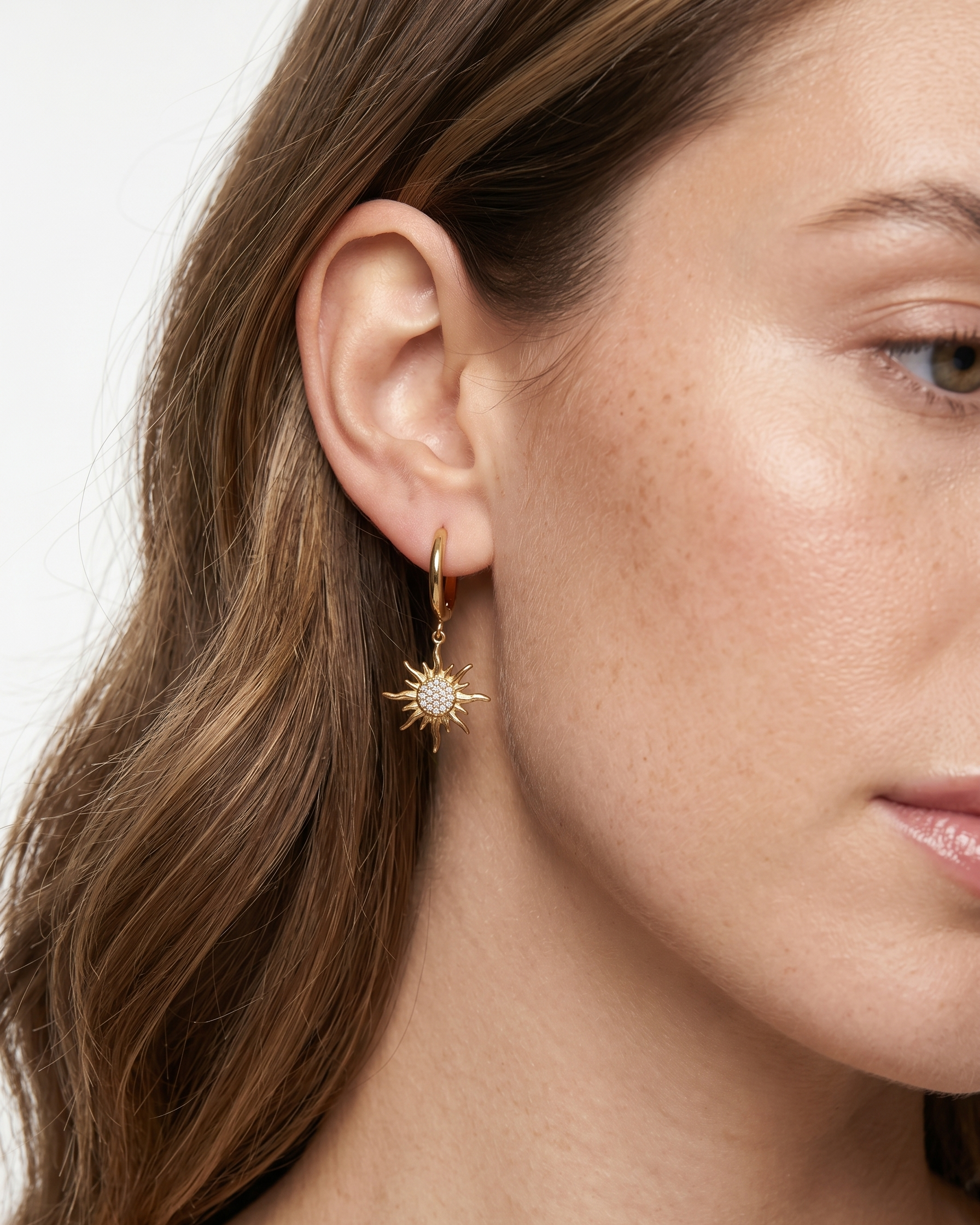 Close-up of a woman wearing a gold hoop earring with a star design.