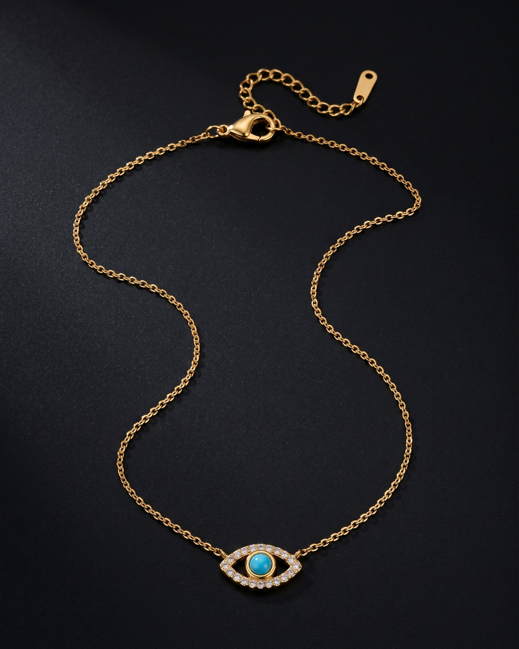 Gold bracelet with a turquoise evil eye charm on a black background
