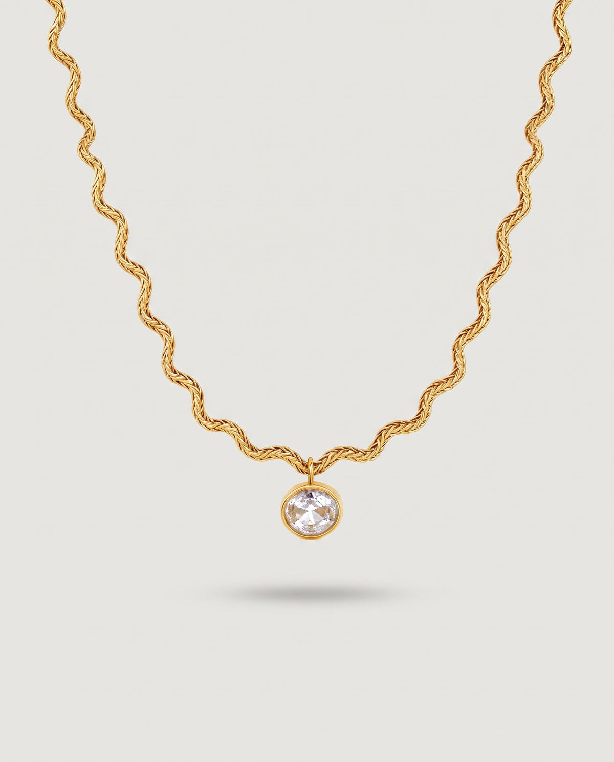 A gold chain necklace with a twisted rope style and a single round clear gemstone pendant, shown against a light gray background.