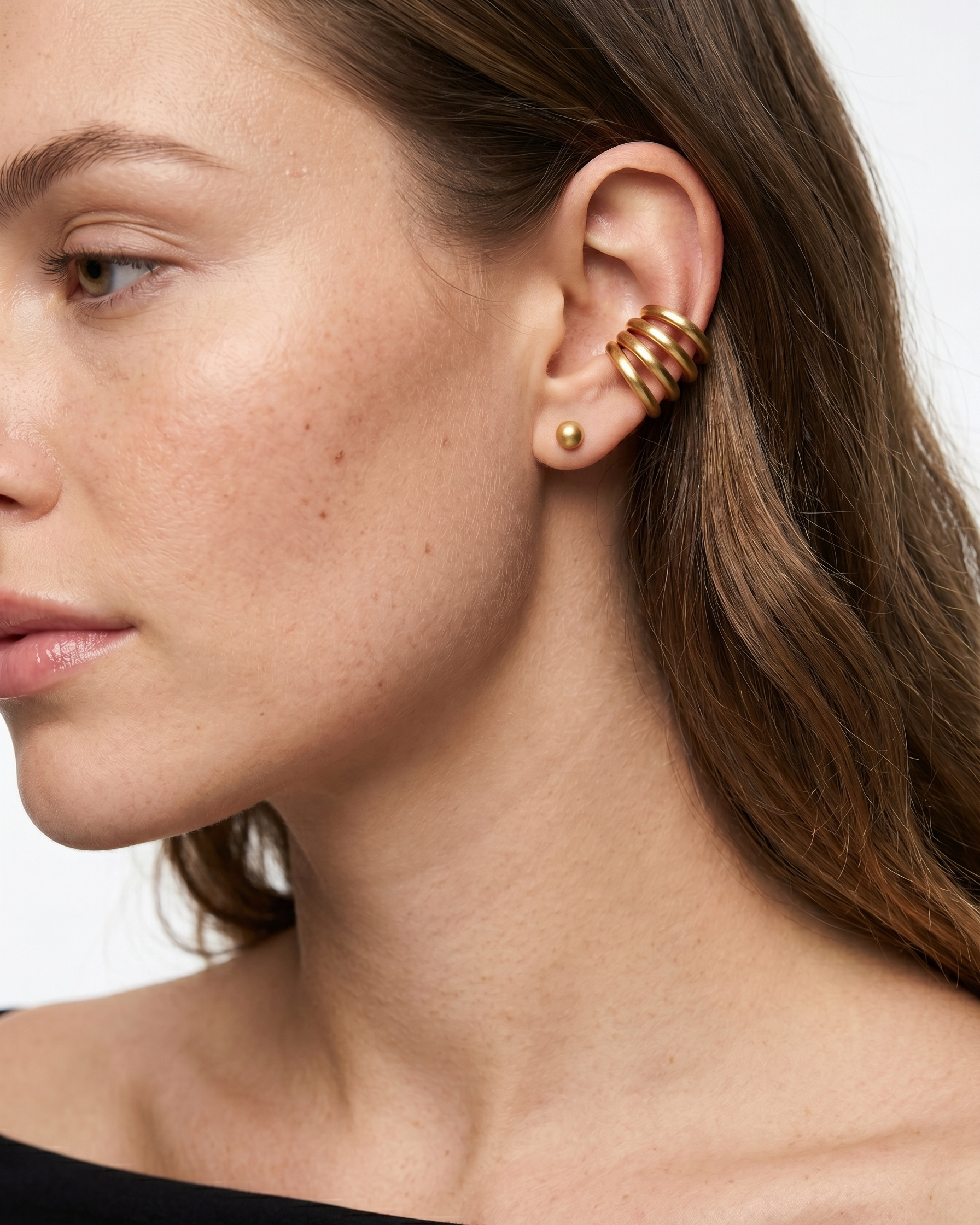 Close-up of a woman wearing a gold earring on a white background